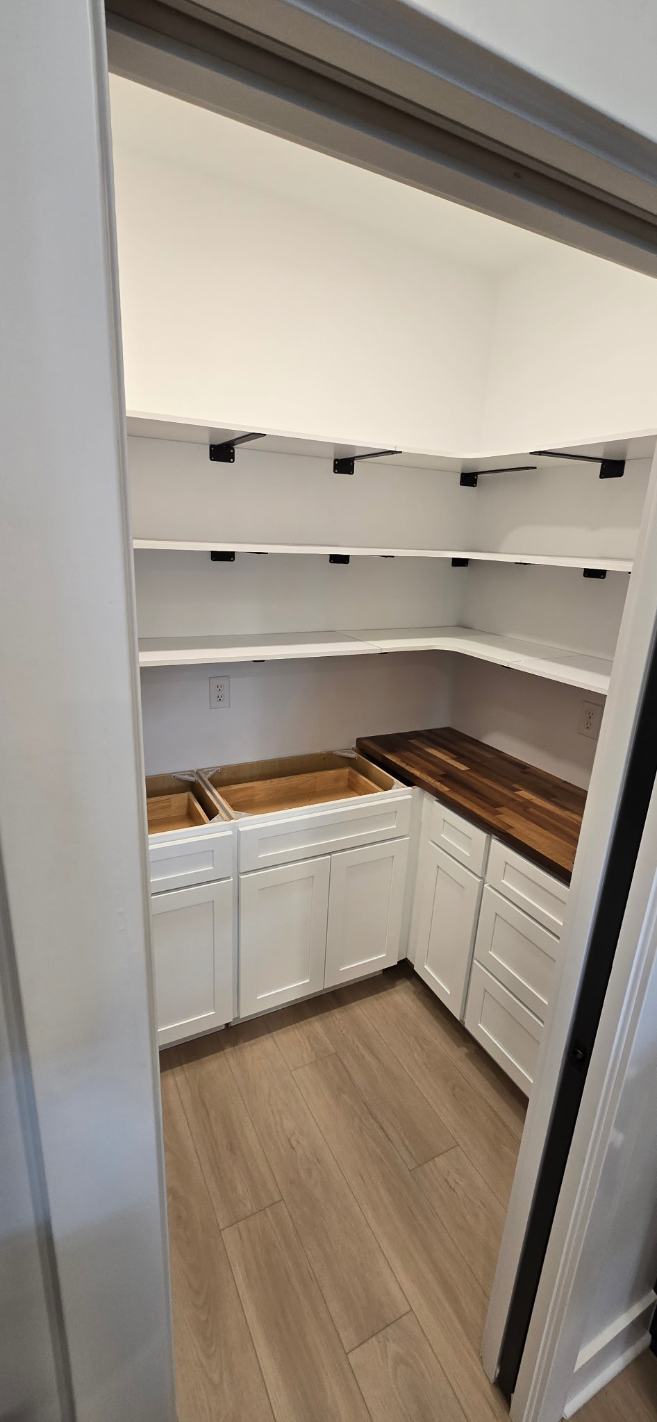 Finished pantry with white cabinetry and butcher-block countertop
